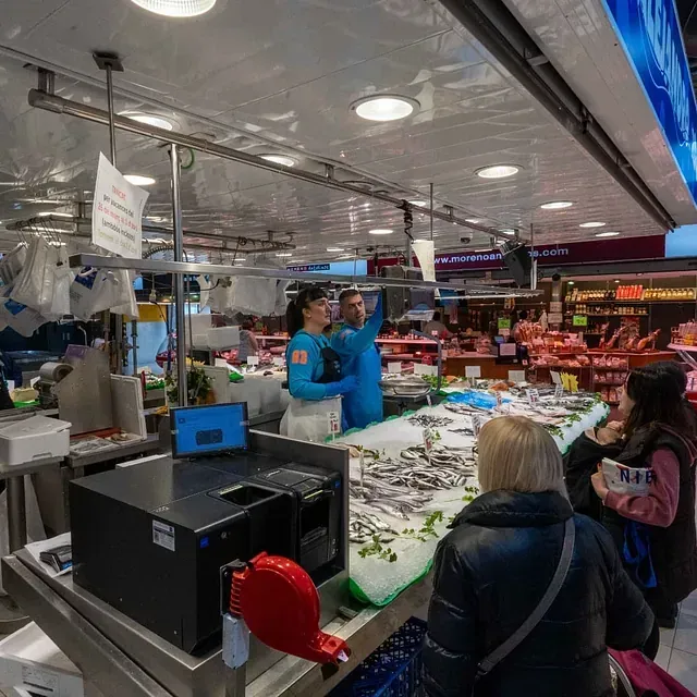 Un grupo de personas están de pie alrededor de una mesa en un mercado.