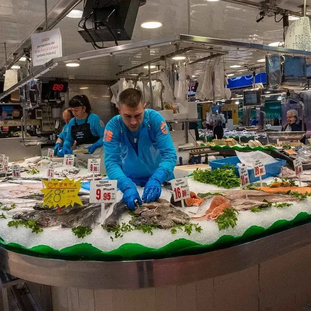 Un hombre con guantes azules está trabajando en un mercado de pescado.