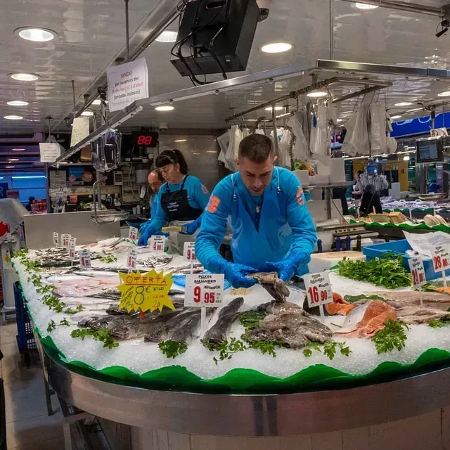 Un hombre con guantes azules está trabajando en un mercado de pescado.