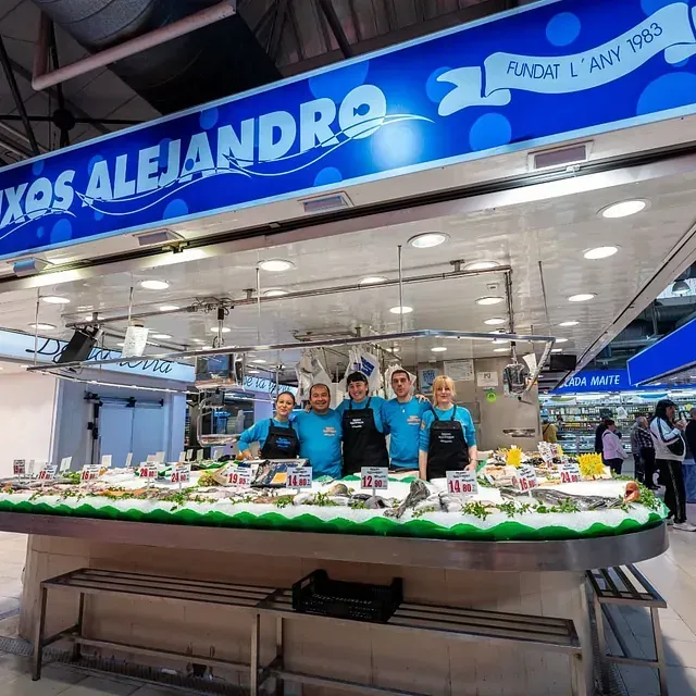 Un grupo de personas de pie frente a un cartel que dice 'xas alejandro'