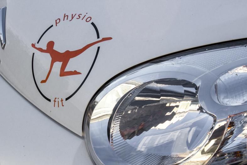 Ein weißes Auto mit einem Aufkleber auf der Motorhaube, auf dem steht „Physio Fit“