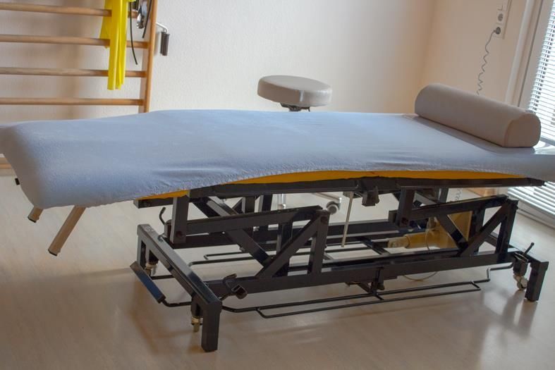 Eine Massageliege mit einer blauen Decke und einem Kissen darauf