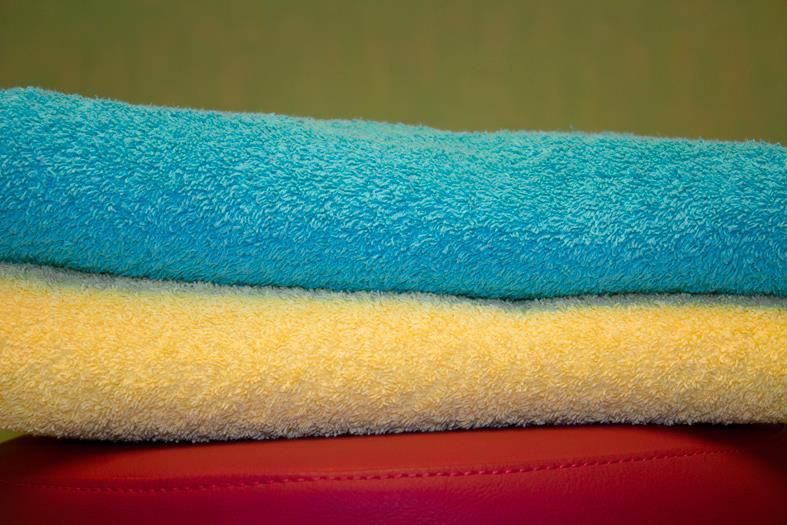 Drei Handtücher liegen übereinander auf einer roten Fläche.