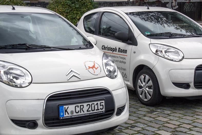 Zwei weiße Autos parken nebeneinander auf einer Ziegelsteinstraße.