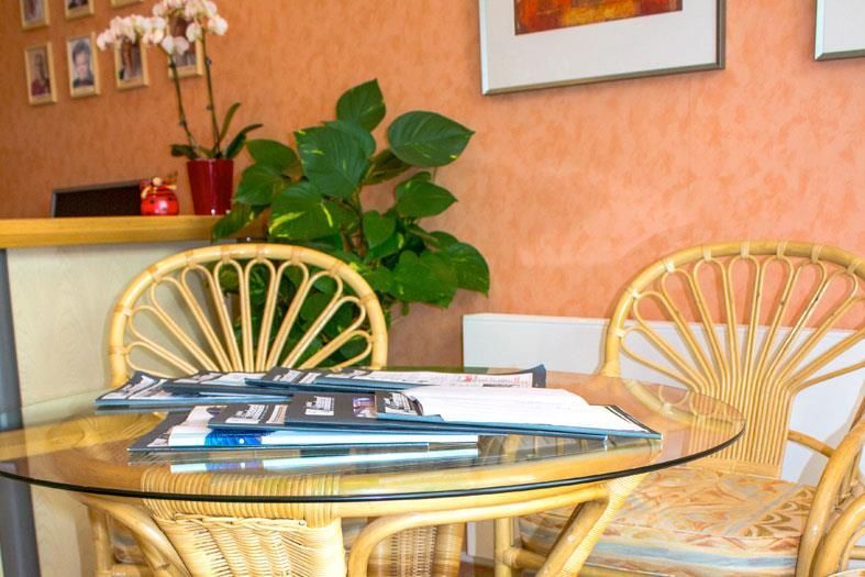 Ein Korbstuhl steht neben einem Glastisch mit Zeitschriften darauf