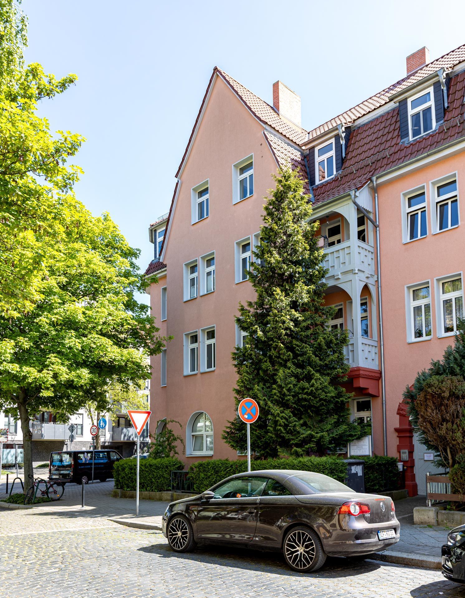 Mehrstöckiges Wohn- und Geschäftshaus mit rosafarbener Fassade in einer innerstädtischen Straße.