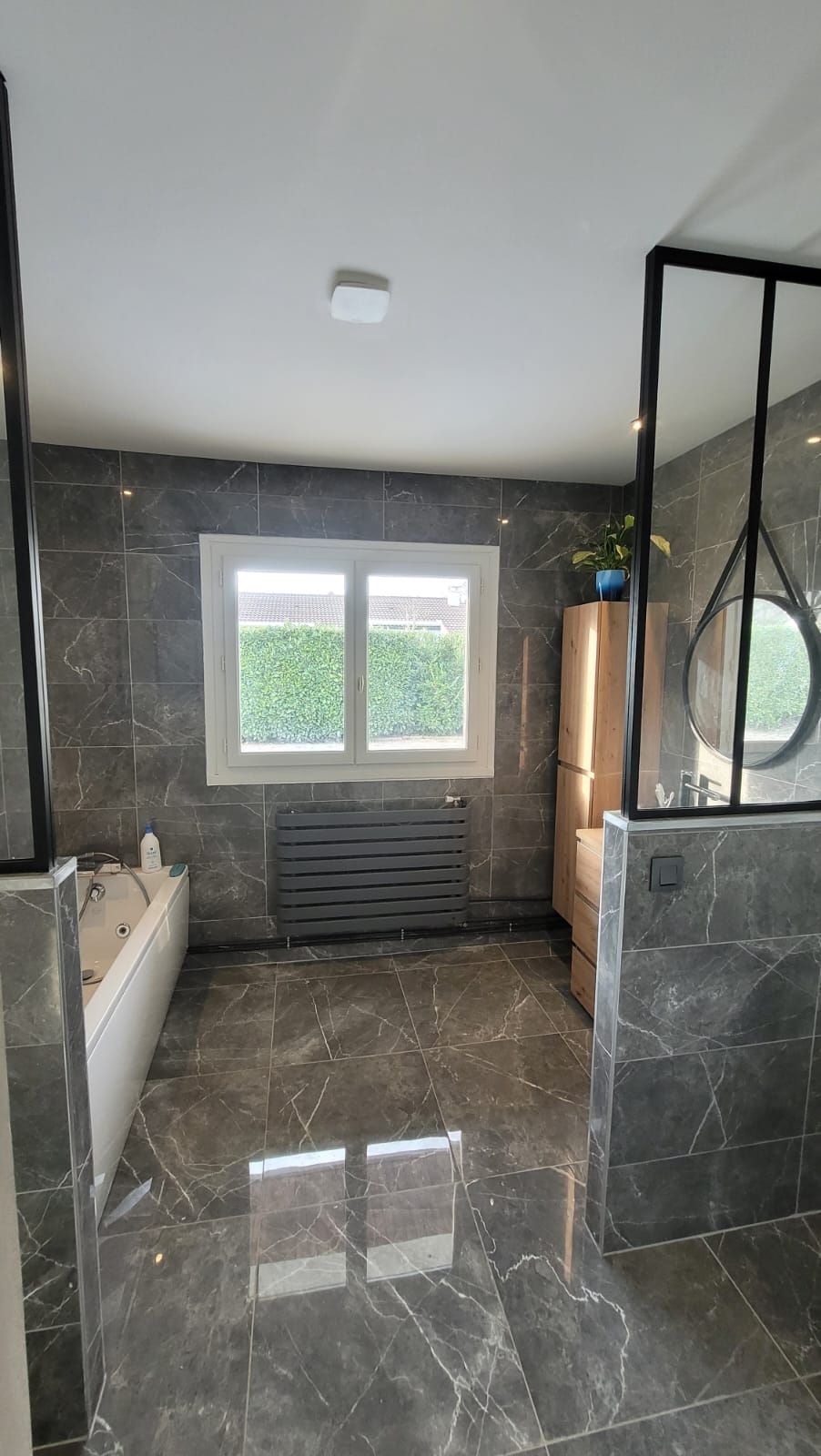 Salle de bains moderne avec carrelage en marbre gris, baignoire blanche.
