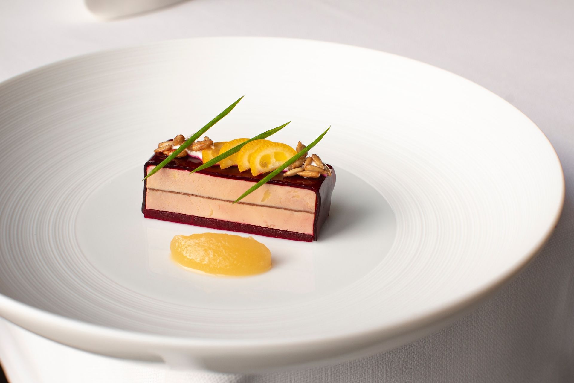 Luxe blauwgroene bar met zachte stoelen, een grote groene vaas en gewelfde deuropeningen.