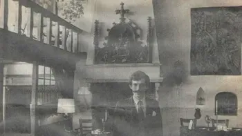 Spookachtige figuur in pak verschijnt in een vintage interieur, naast een open haard en een trap. Zwart-wit.