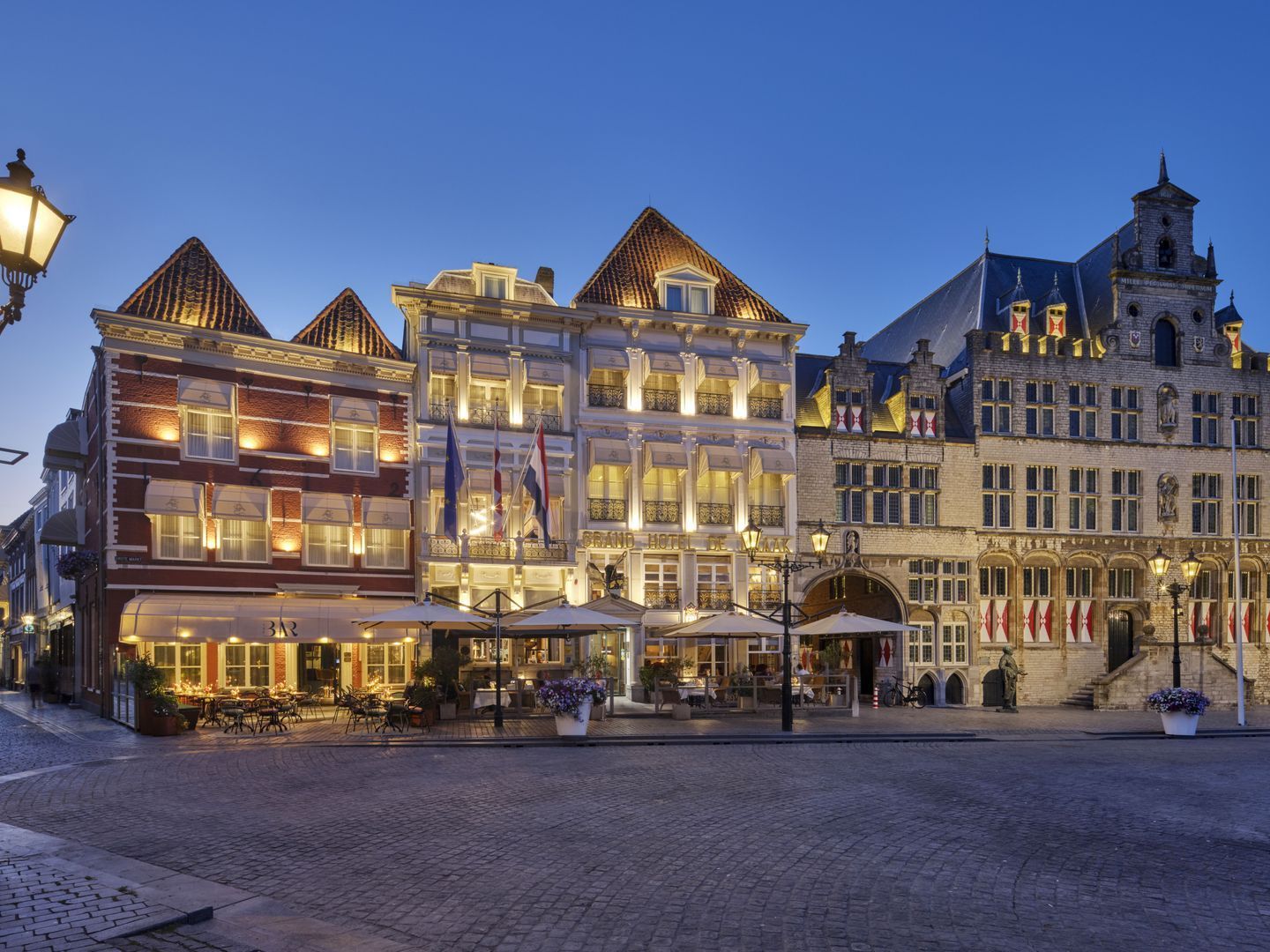Geplaveide straat in een Europees stadje met veel winkels. Een stel wandelt richting de verre toren.