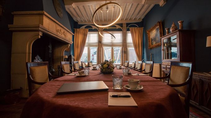 Mensen in formele kleding poseren met een sierlijk embleem op een tafel binnenshuis.