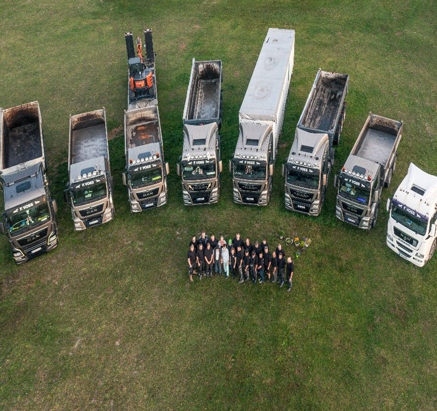 Eine Gruppe von Lastwagen steht aufgereiht auf einer Wiese.