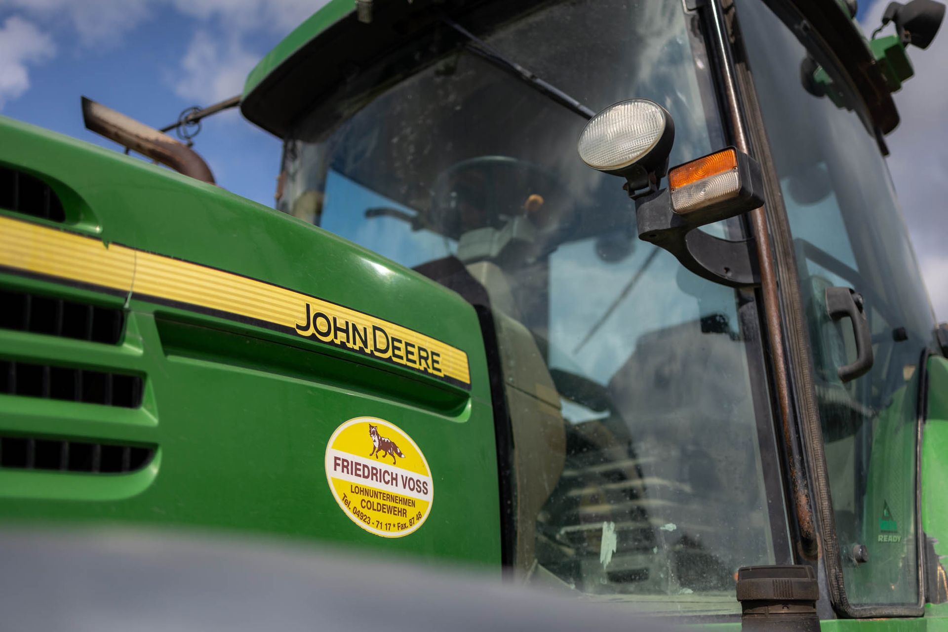 Ein Mann fährt einen grünen John Deere-Traktor.