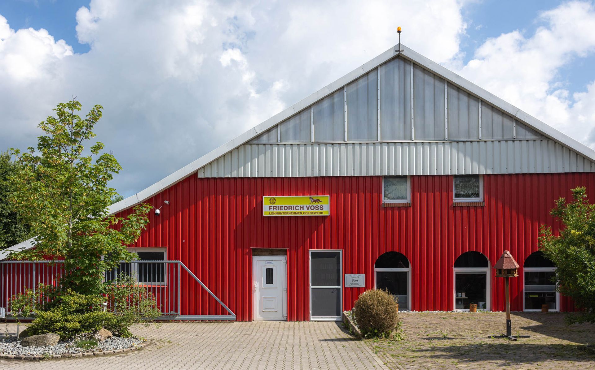 Ein großes rotes Gebäude mit weißem Dach ist von Bäumen umgeben.