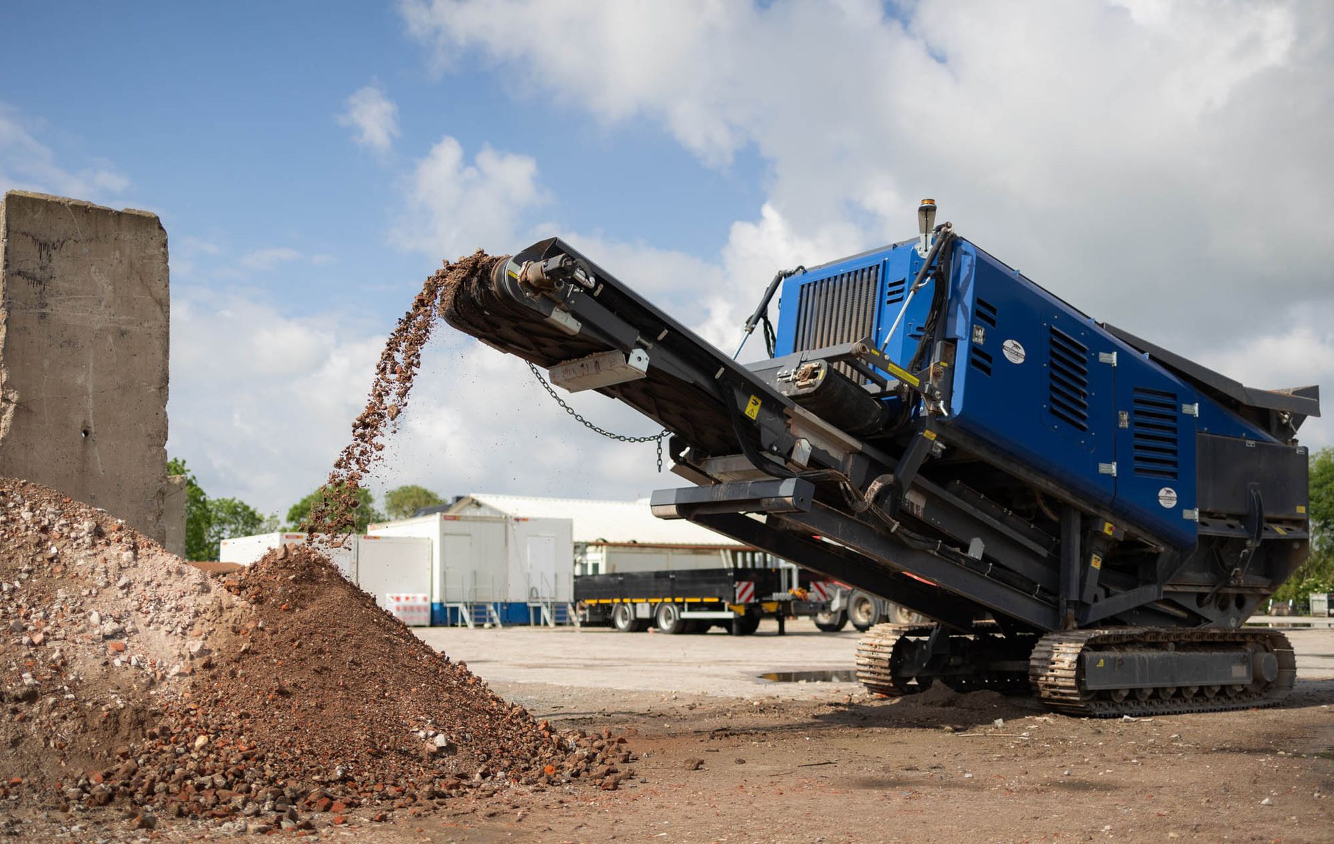 Eine Maschine schüttet Steine auf einen Erdhaufen.
