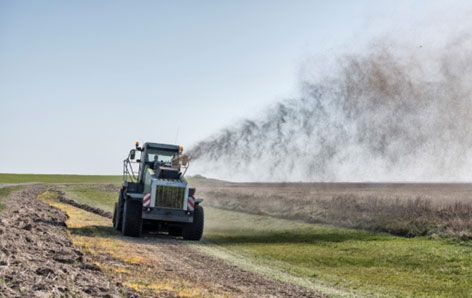 Ein Traktor sprüht Dünger auf einem Feld.