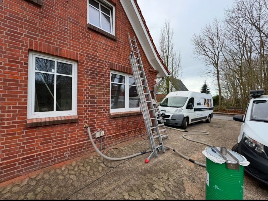 An der Seite eines Backsteingebäudes steht neben einem weißen Lieferwagen eine Leiter.