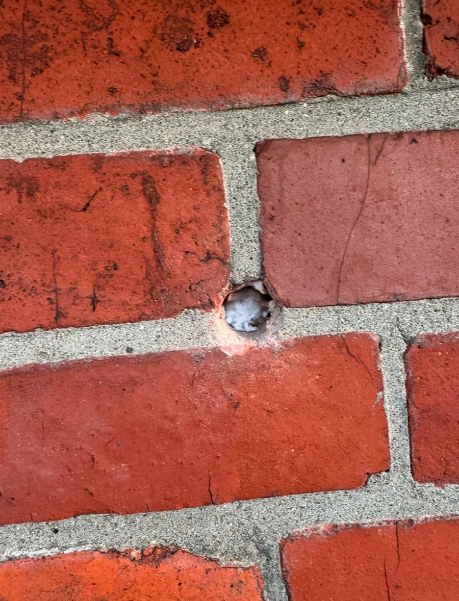 Eine Nahaufnahme einer Ziegelmauer mit einem Loch darin