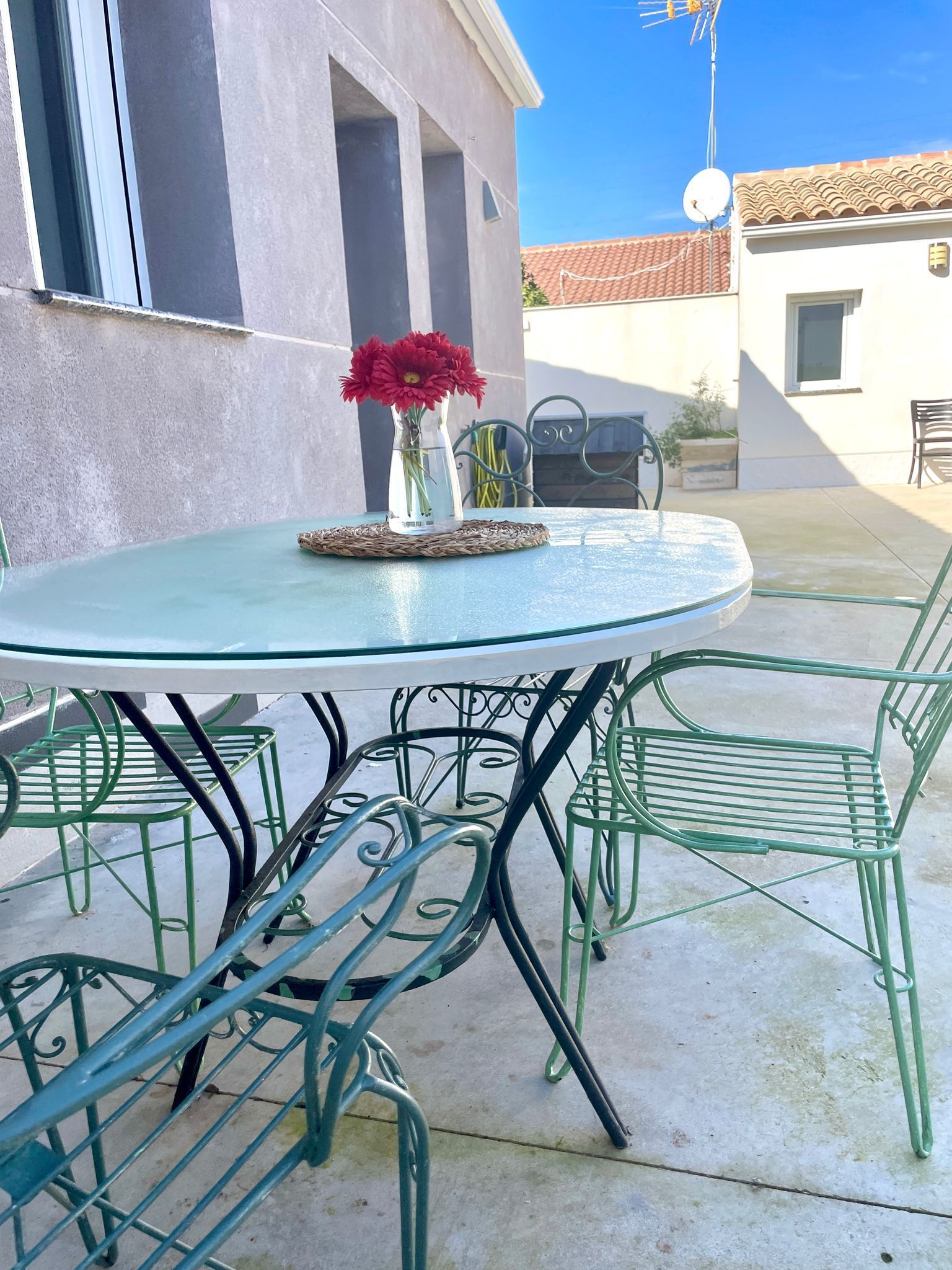 Una mesa con un jarrón de flores rojas encima.