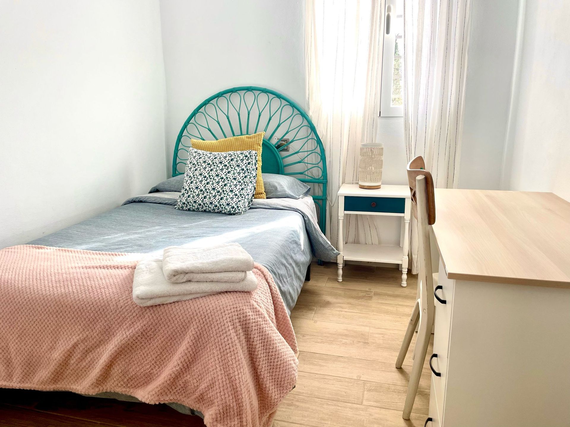 Un dormitorio con una cama, mesita de noche, escritorio y silla.