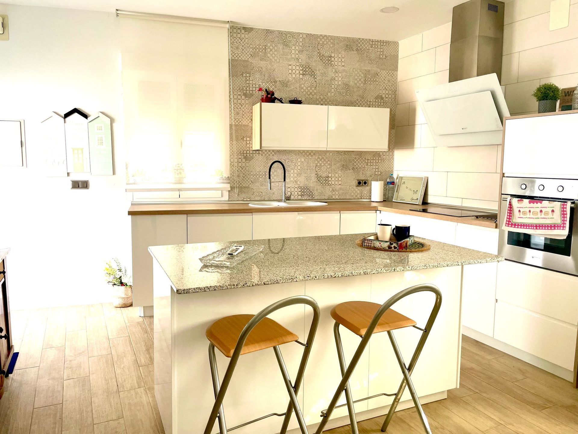 Una cocina con una gran isla y dos taburetes.