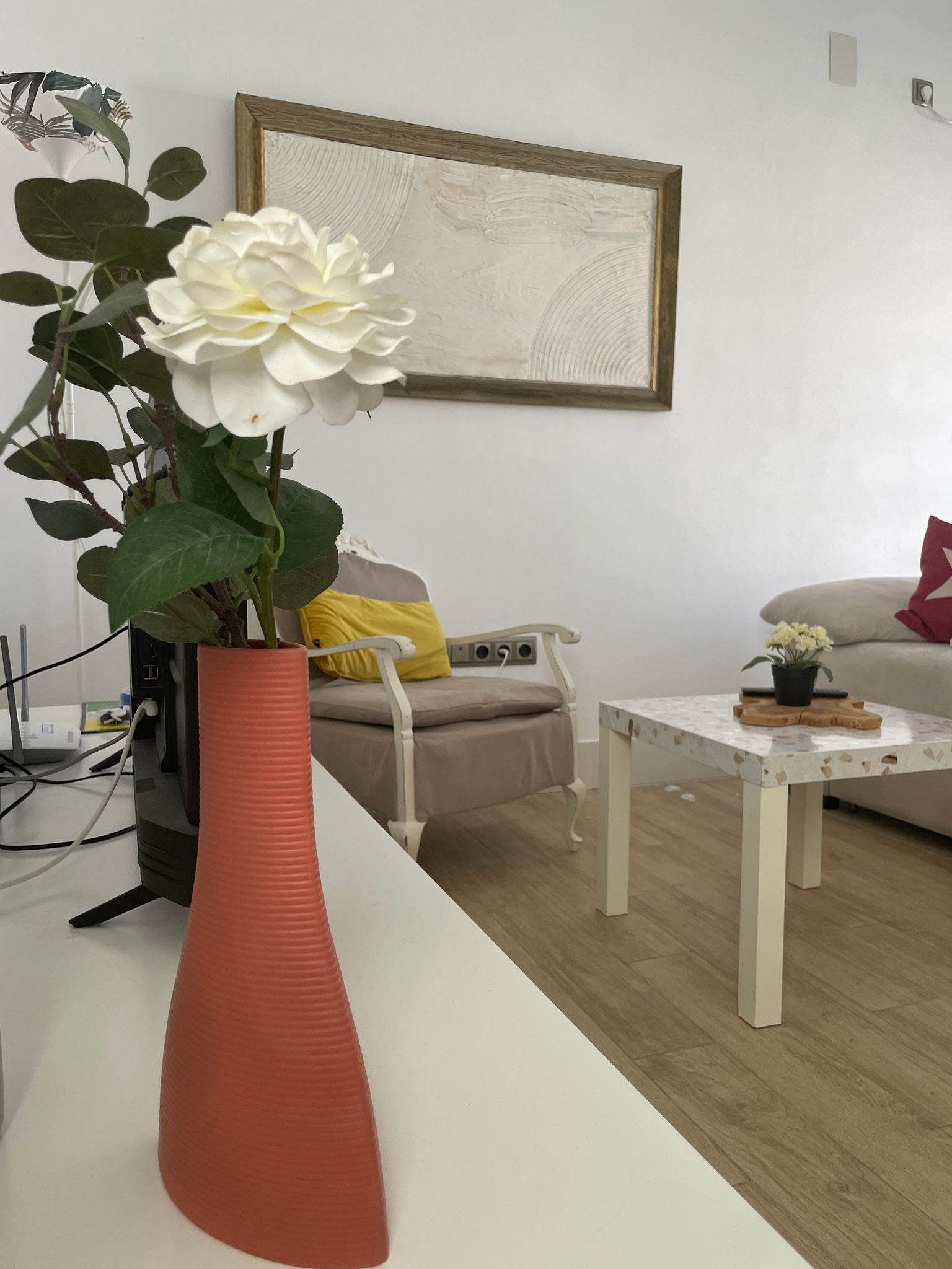 Un jarrón con una flor se encuentra sobre una mesa en una sala de estar.