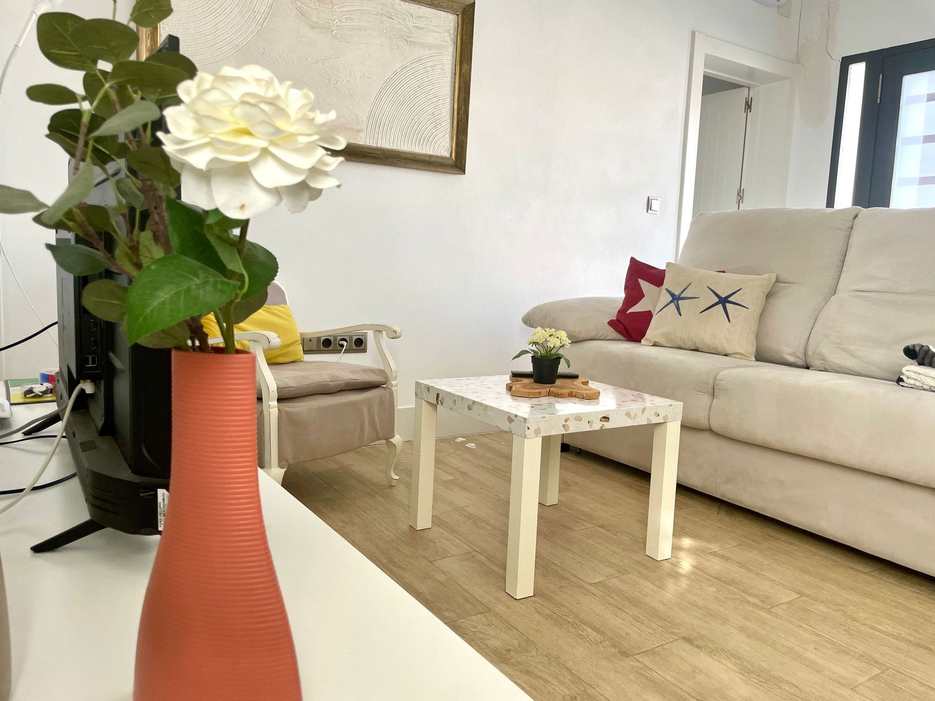 Una sala de estar con un sofá, una silla, una mesa y un jarrón de flores.