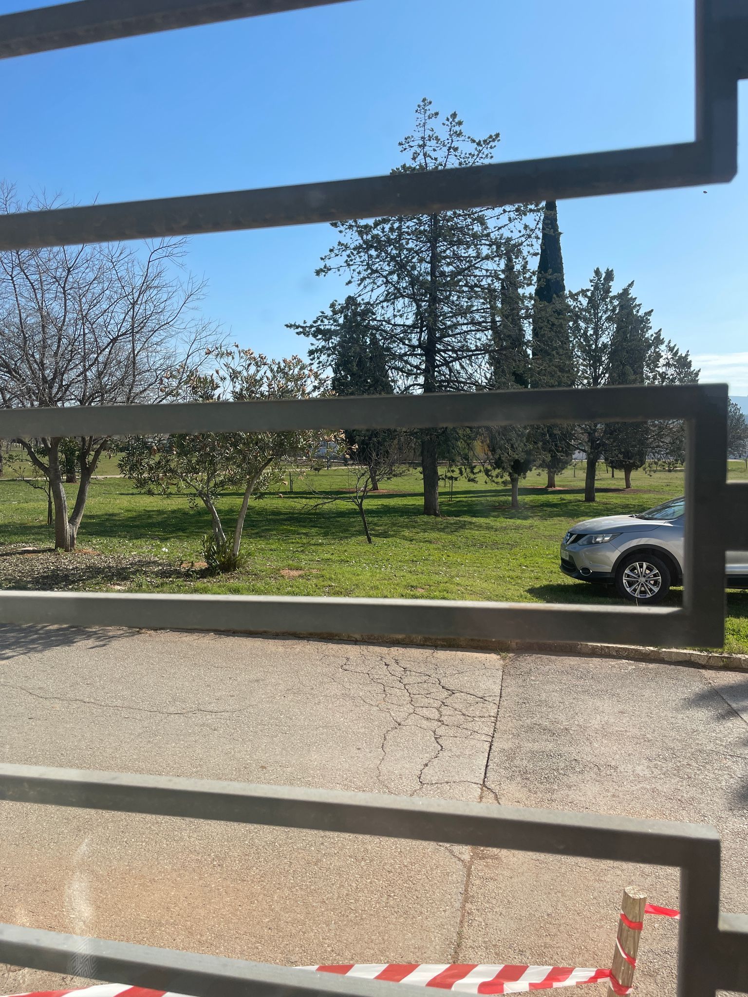 Un coche está aparcado al costado de la carretera detrás de una valla.