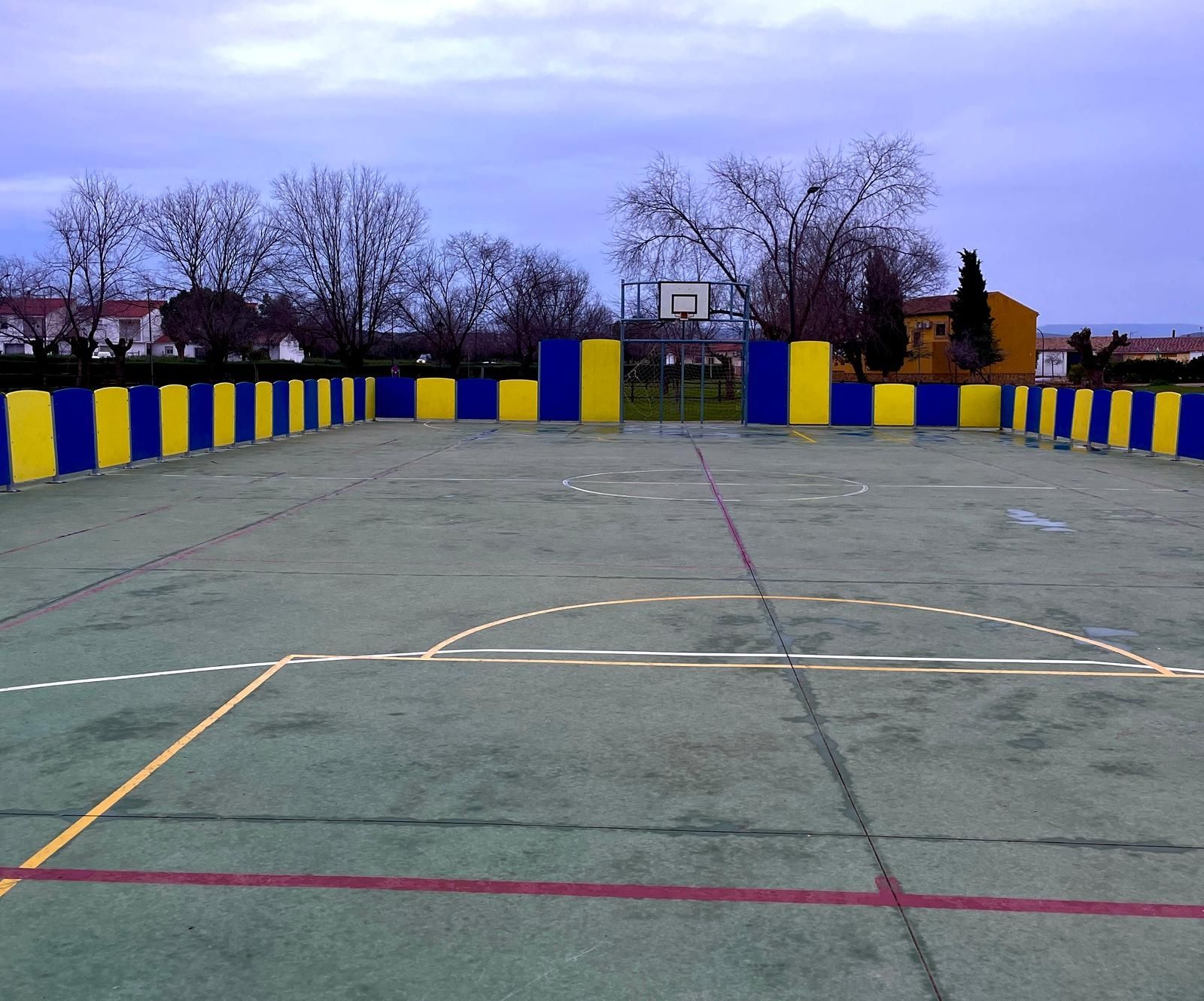 Una cancha de baloncesto con paredes amarillas y azules y un aro de baloncesto.