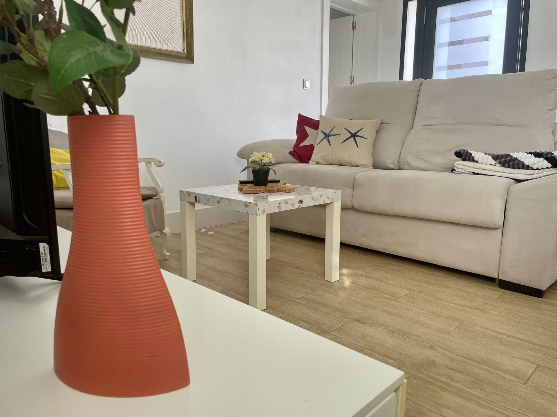 Una sala de estar con sofá, mesa y jarrón.