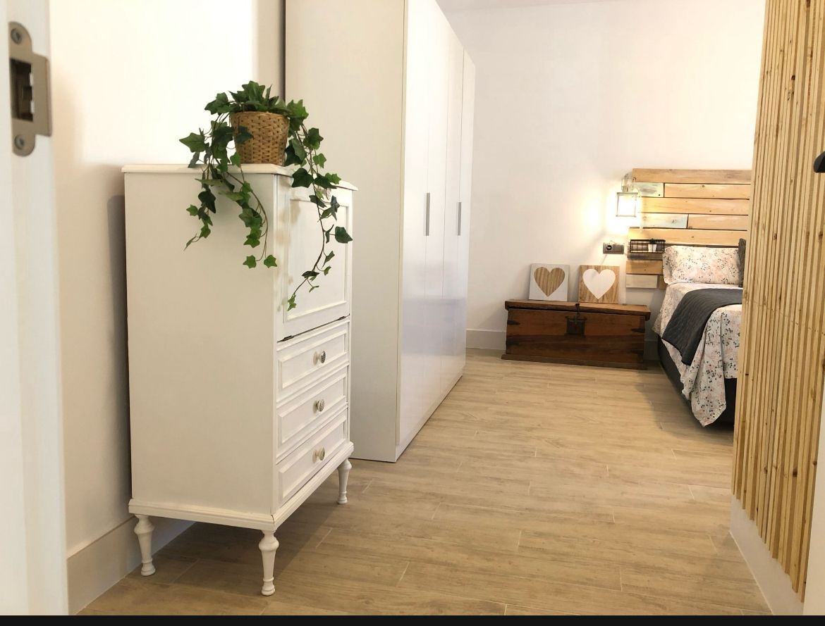 Un dormitorio con una cómoda blanca y una cama.