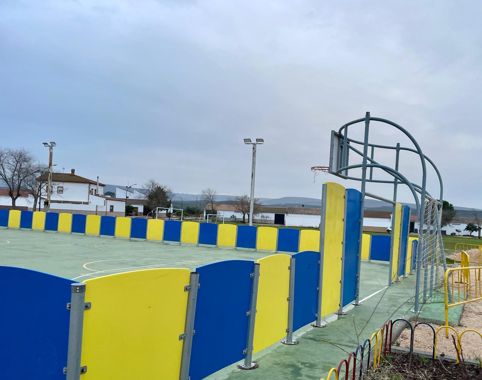 Una valla azul y amarilla rodea una cancha de baloncesto.