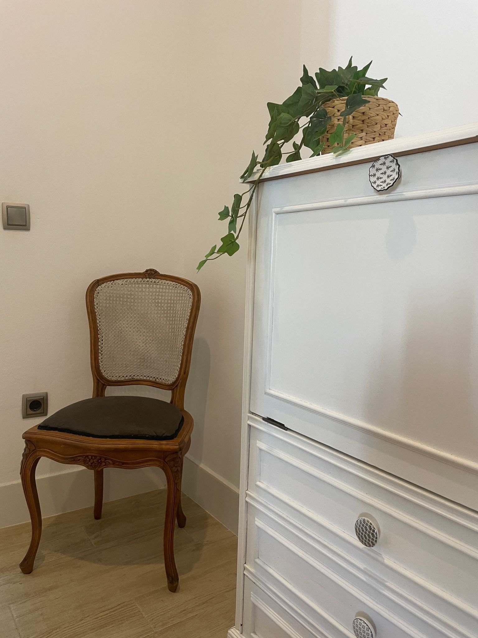 Una silla está al lado de una cómoda blanca en una habitación.