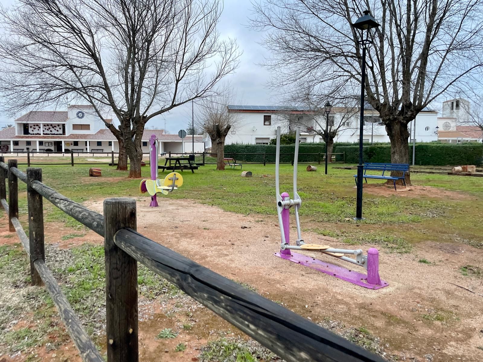 Una valla de madera rodea un patio de juegos en un parque.