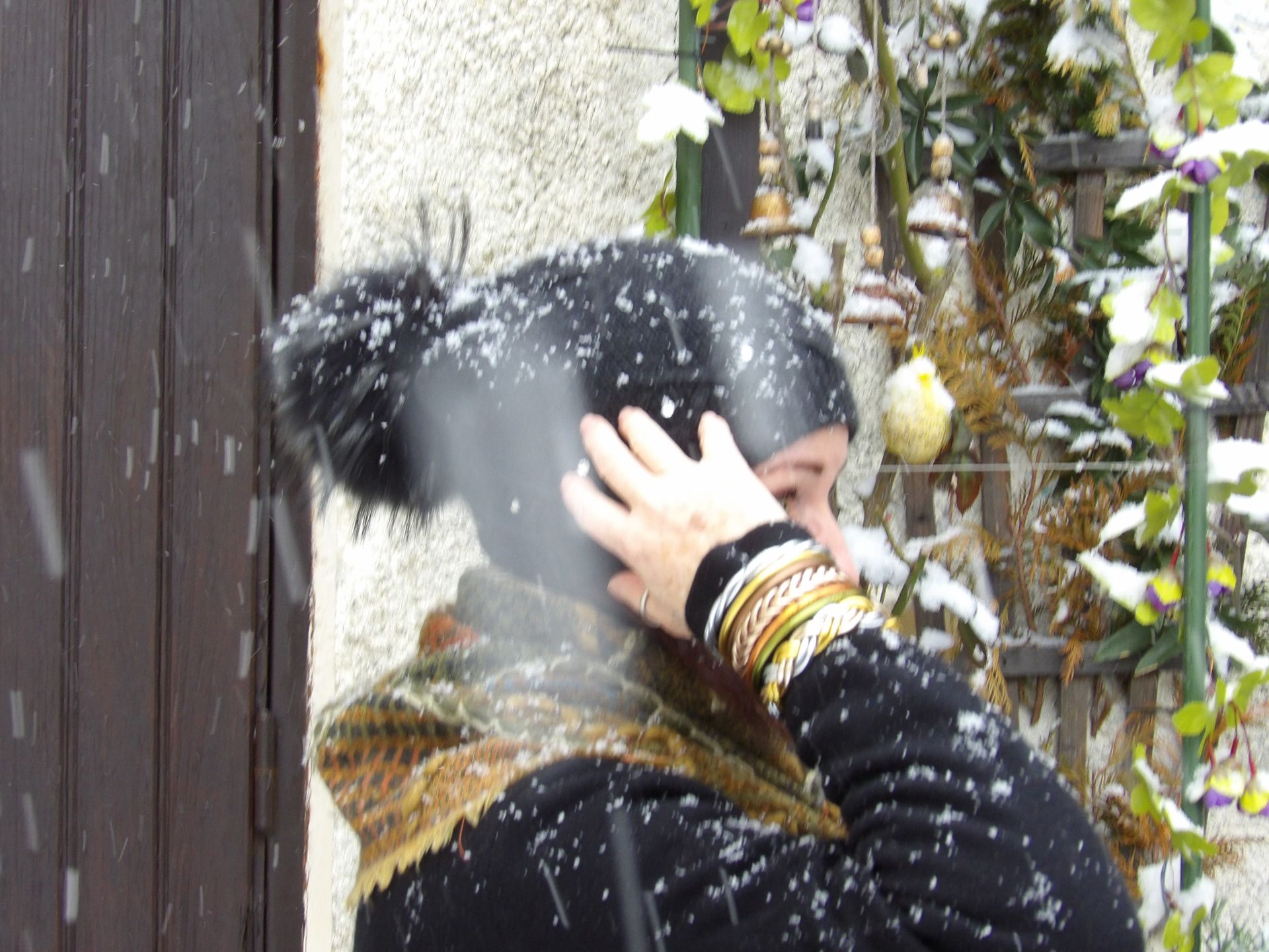 gros plan sur une main tenant un bonnet sur la tête d'une femme avec les joncs bouddhistes colorés en arrière plan de la végétation sous la neige