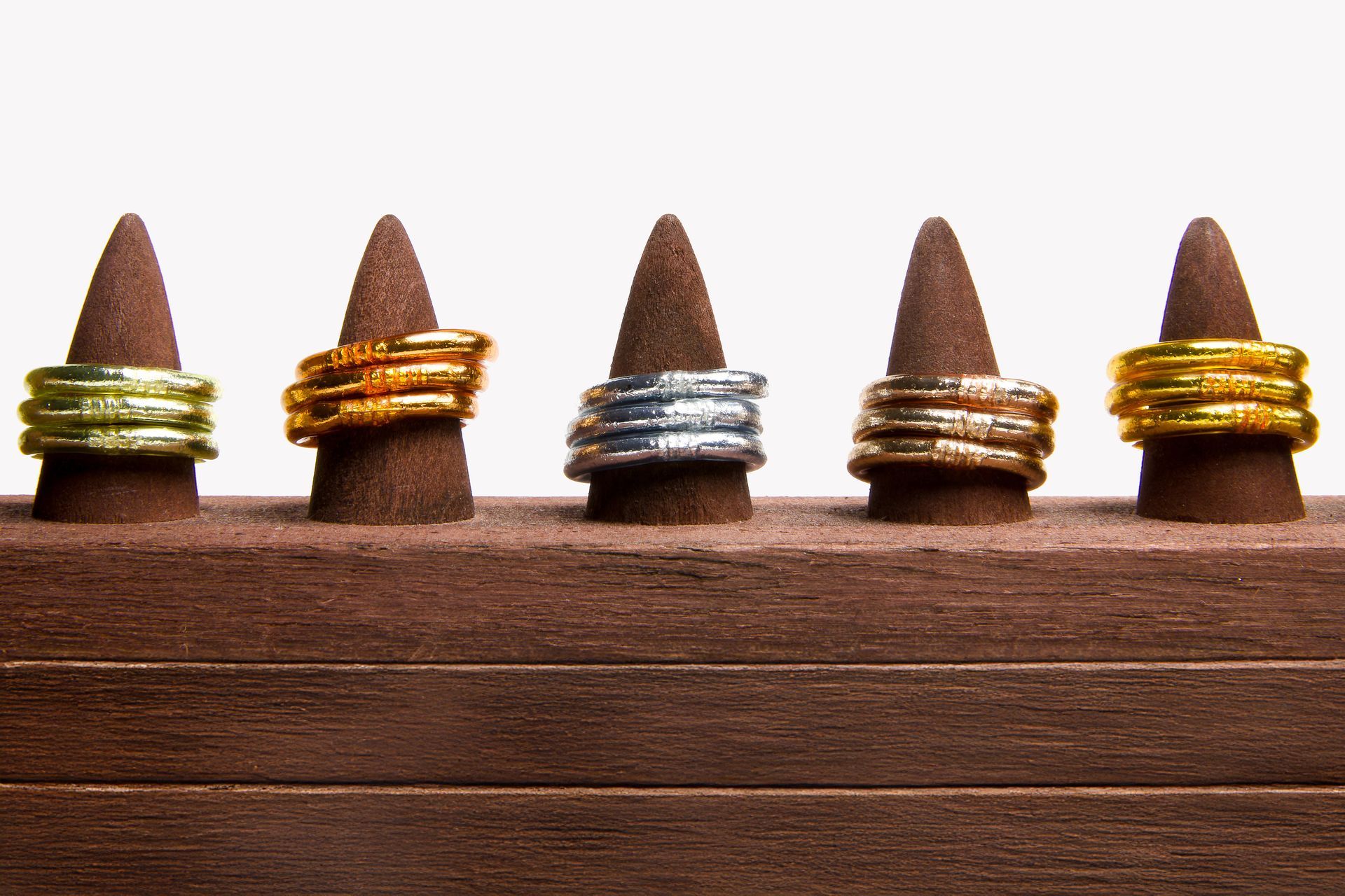 Cinq anneaux colorés présentés sur des supports en bois.