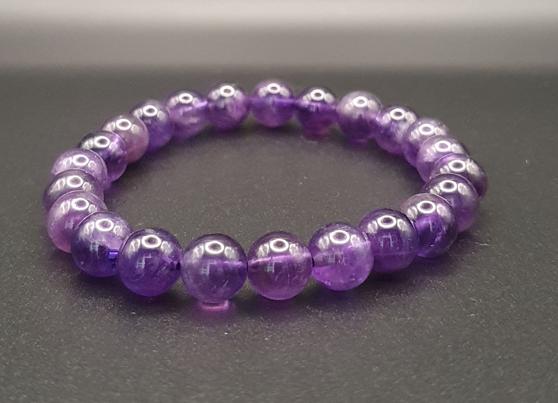 Bracelet violet sur une table noire.