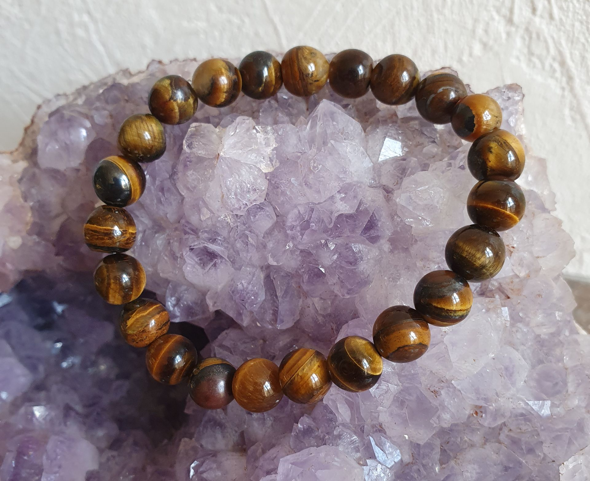 Bracelet en perles œil-de-tigre sur un cristal d'améthyste violette.
