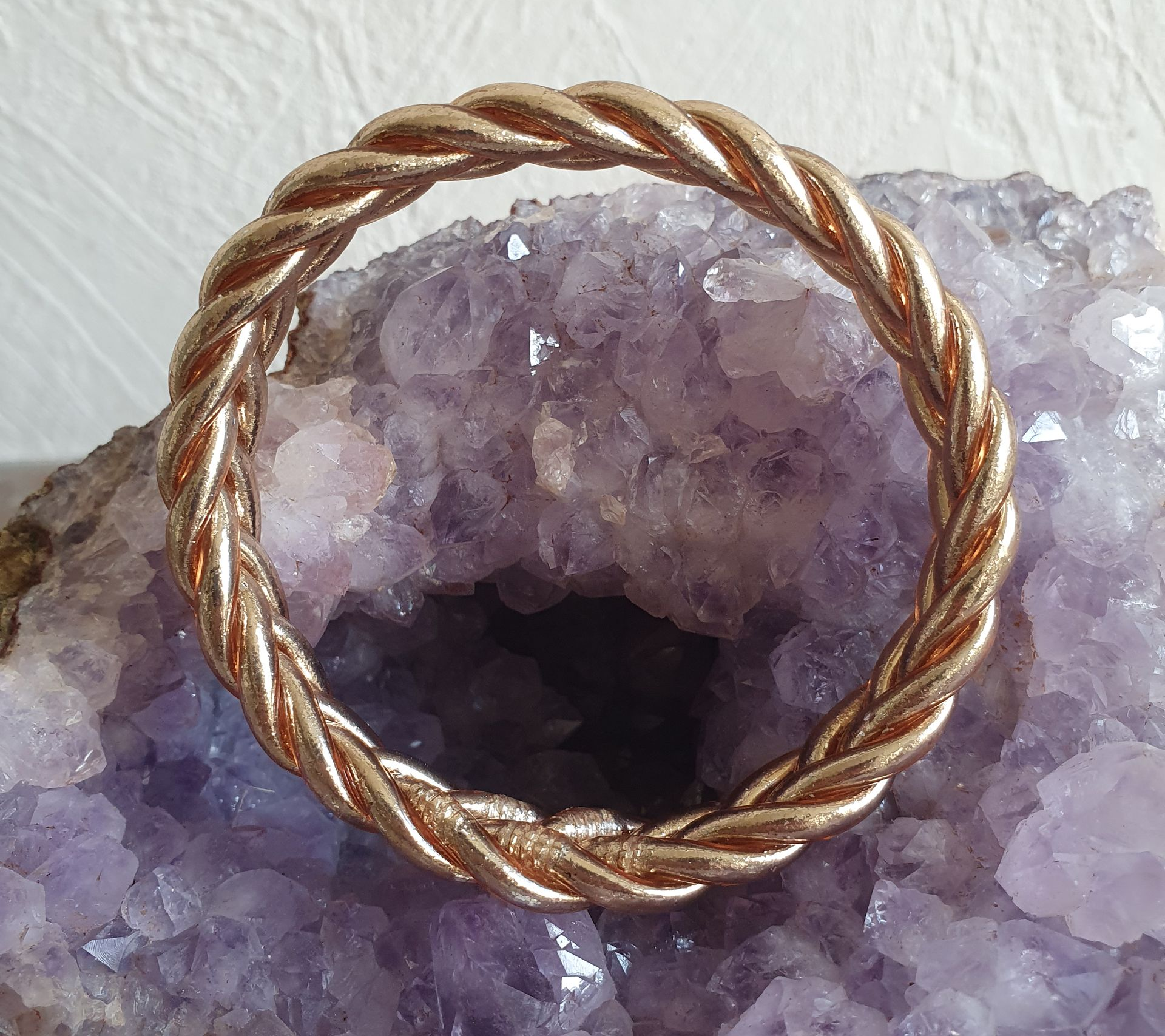Bracelet tressé en or rose sur une géode de cristal d'améthyste violette.