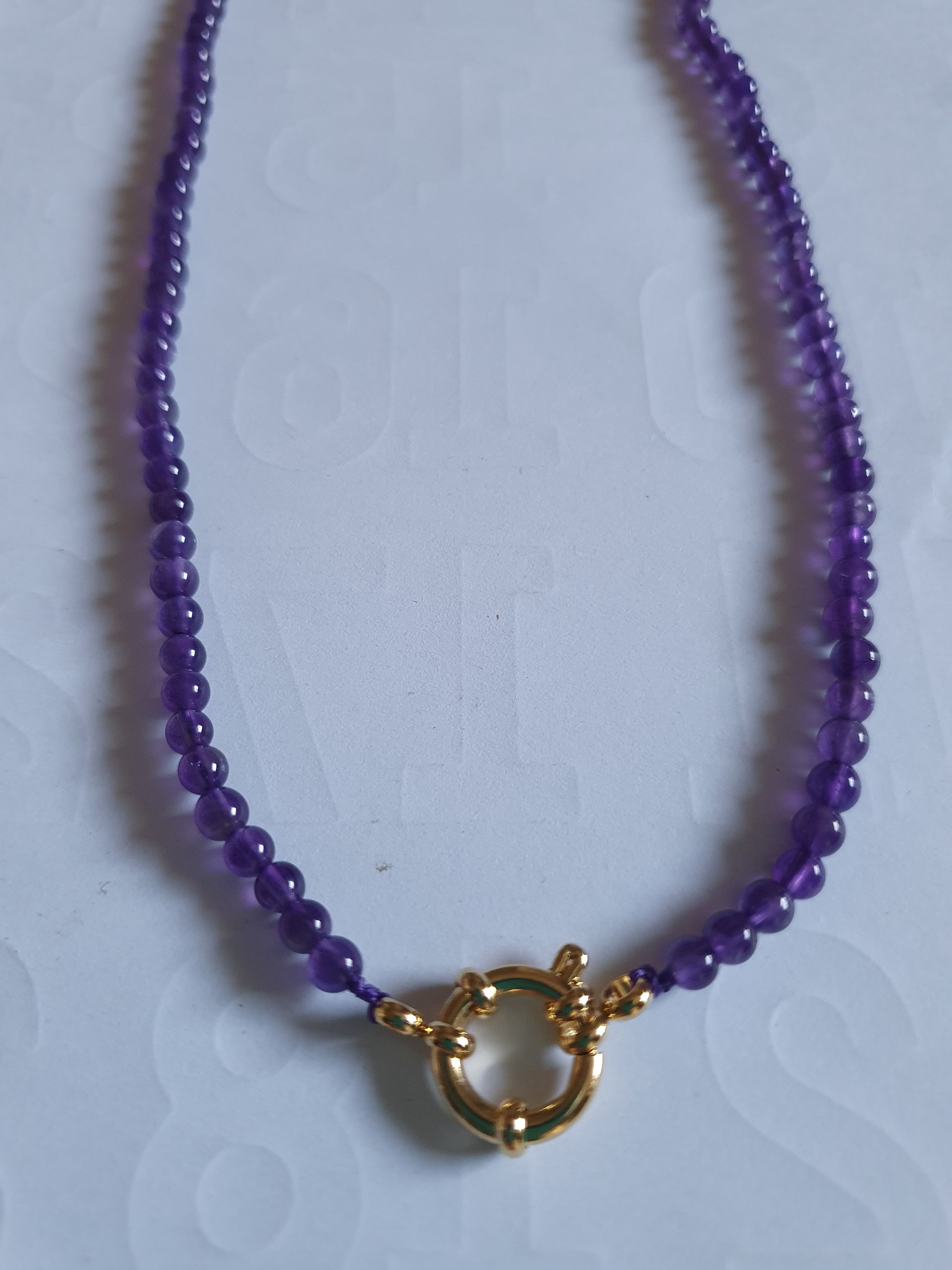 Collier de perles violettes avec fermoir doré.
