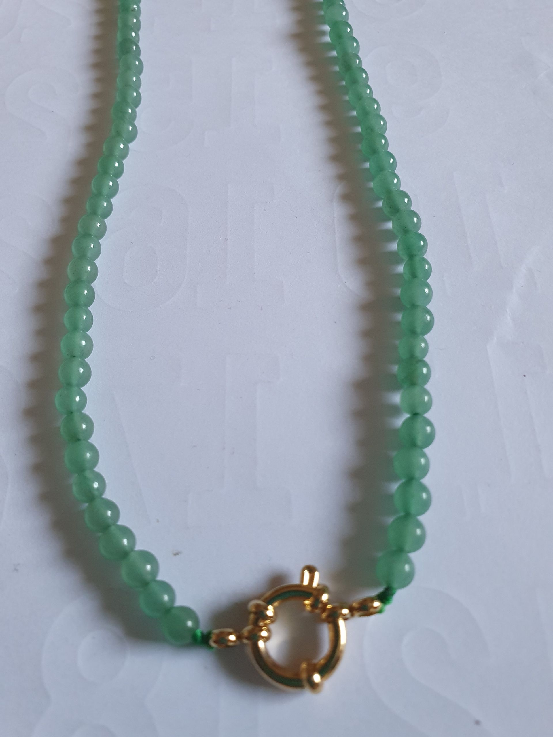 Collier de perles vertes avec fermoir doré.