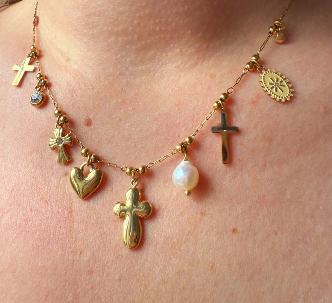 Collier en or orné de divers pendentifs, dont des croix, un cœur et une perle.