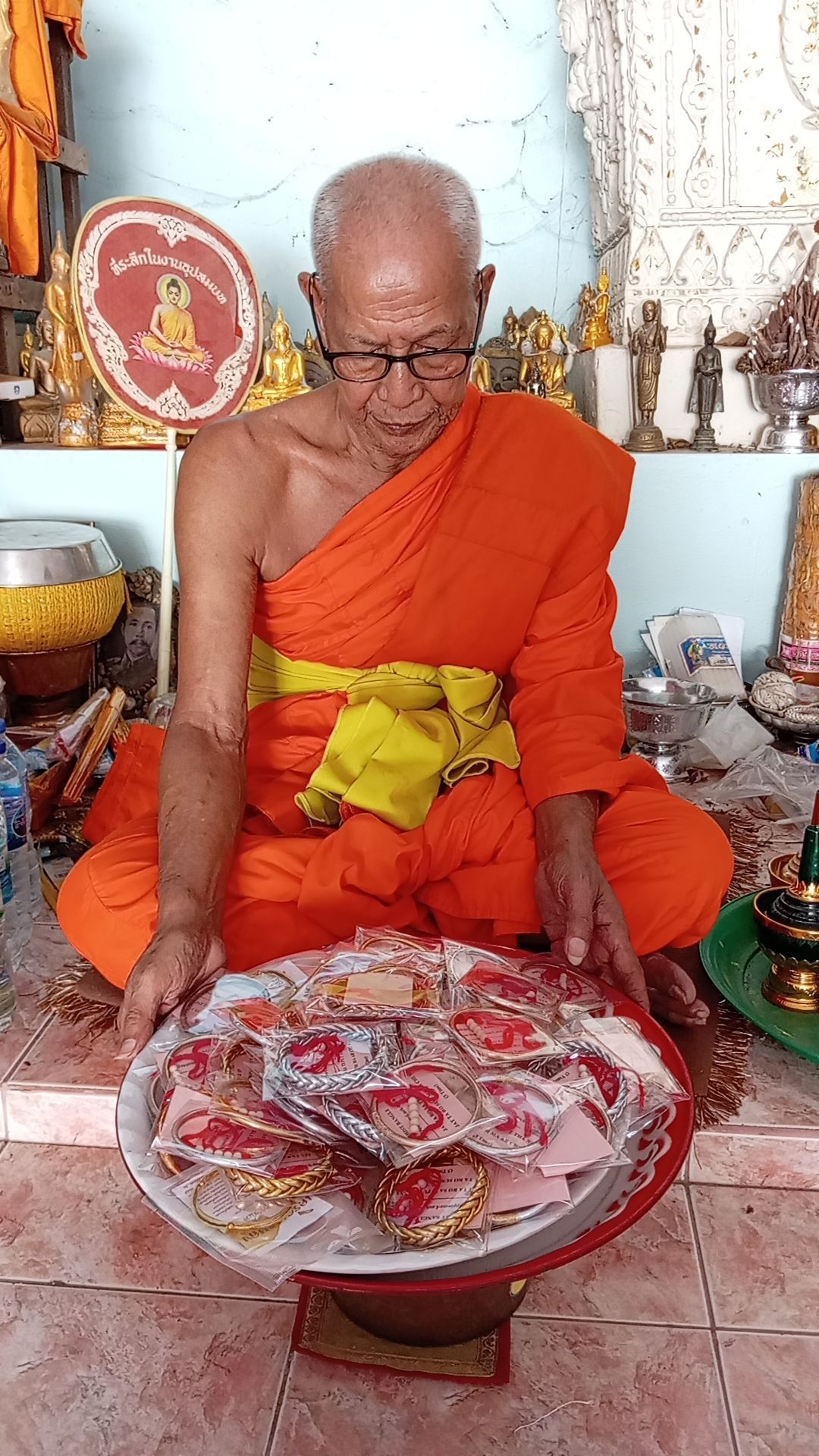 un moine bouddhiste assis dans son temple de Thaïlande tenant un récipient rempli de joncs 