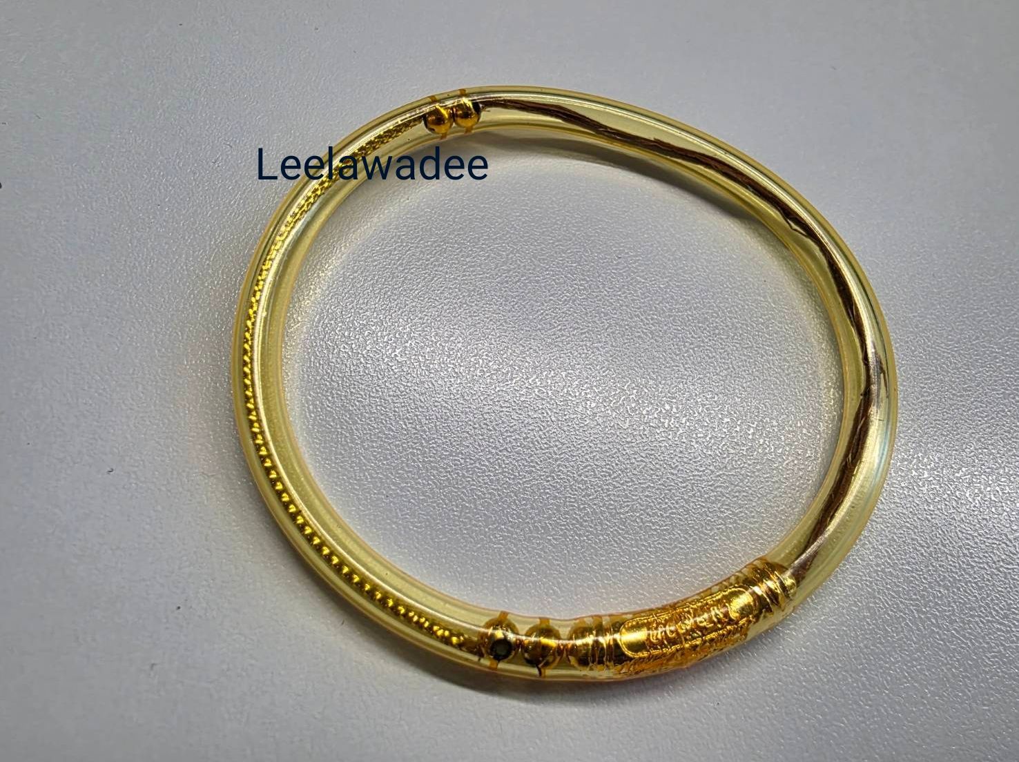 Bracelet en or orné de motifs détaillés sur fond blanc.