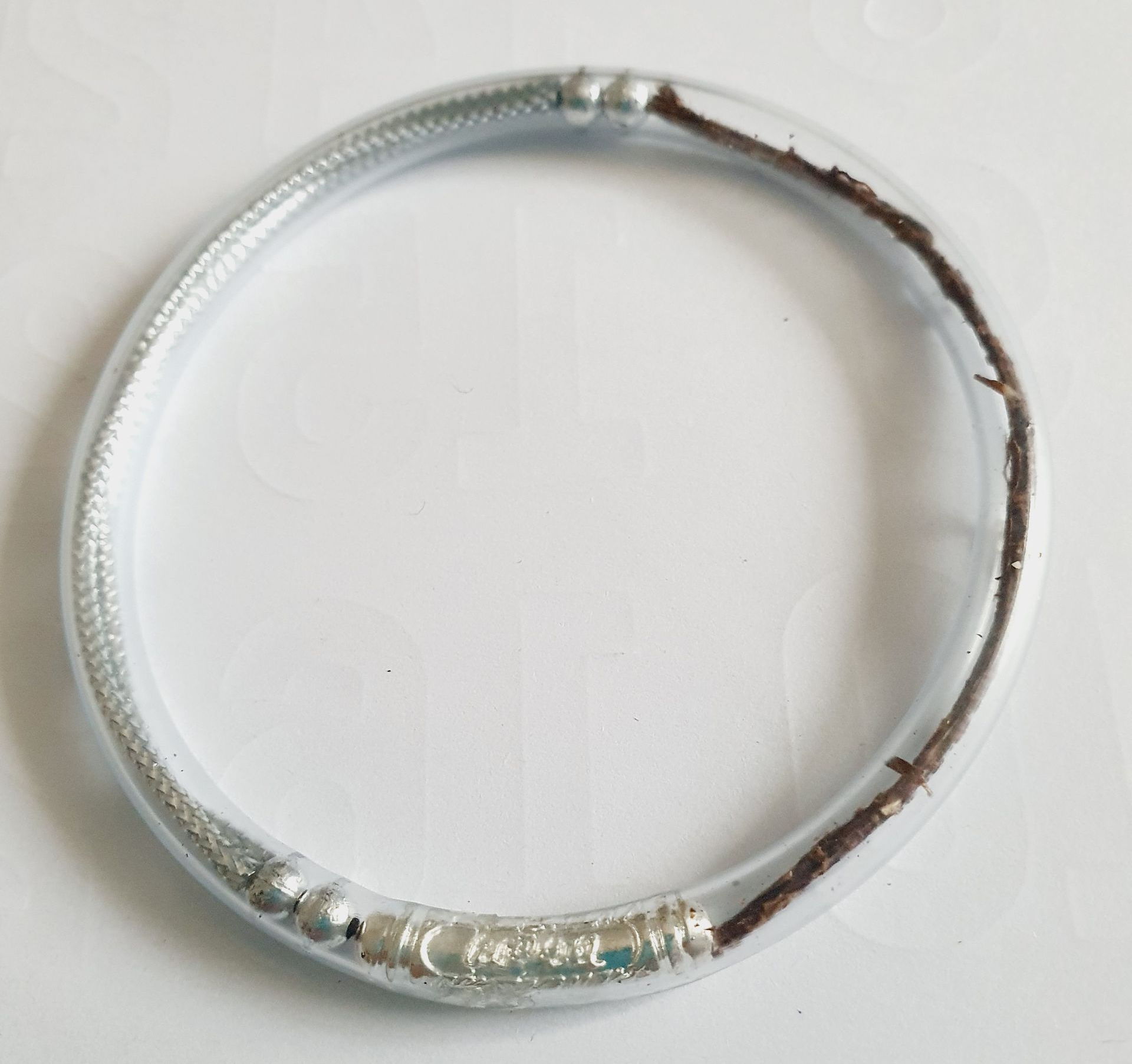 Bracelet en argent avec une brindille brun foncé insérée dans du plastique transparent.