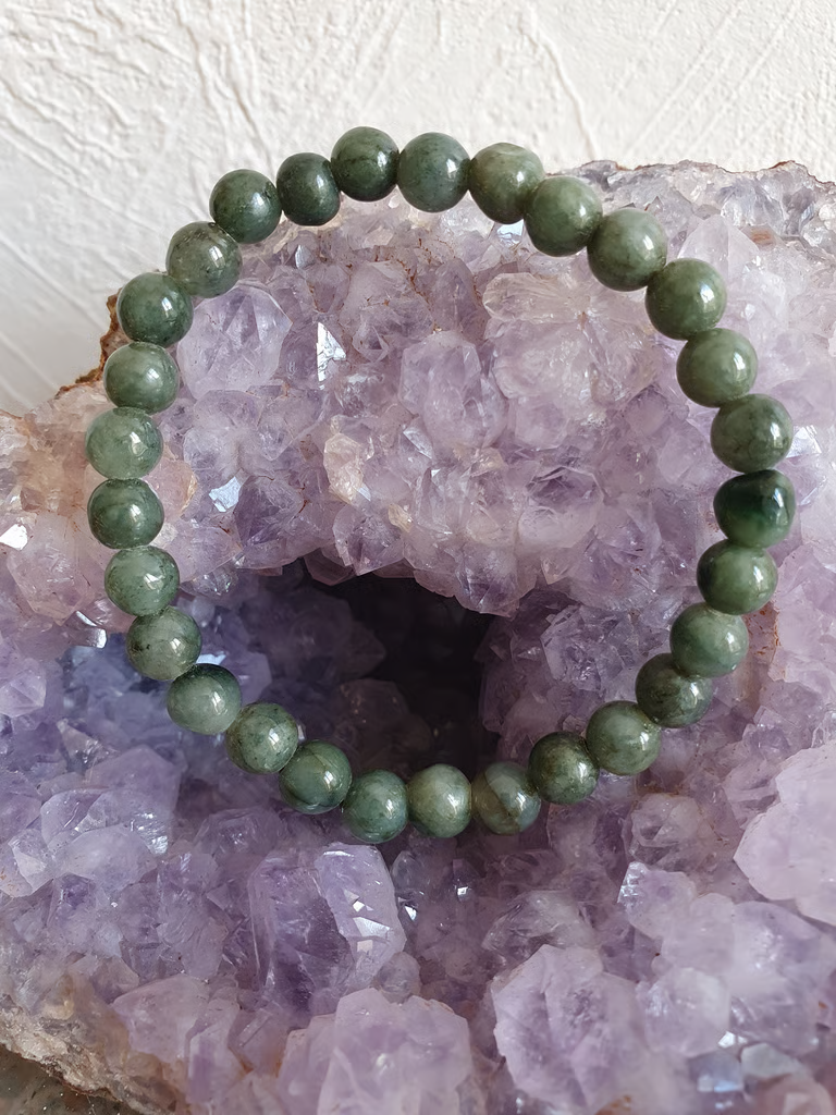 Bracelet de perles vertes sur une géode de cristal violet.