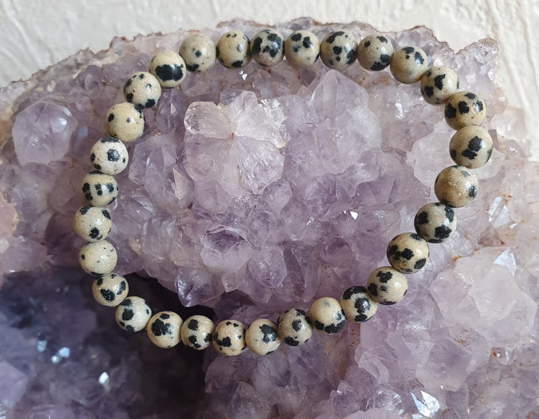 Bracelet de perles de jaspe dalmatien sur un amas d'améthystes violettes.