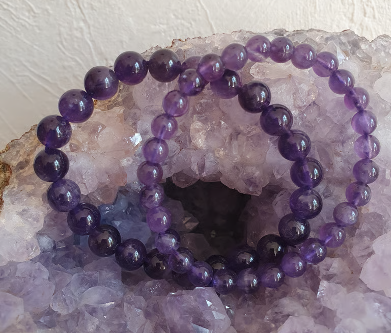 Bracelets de perles d'améthyste violette reposent sur une géode d'améthyste.