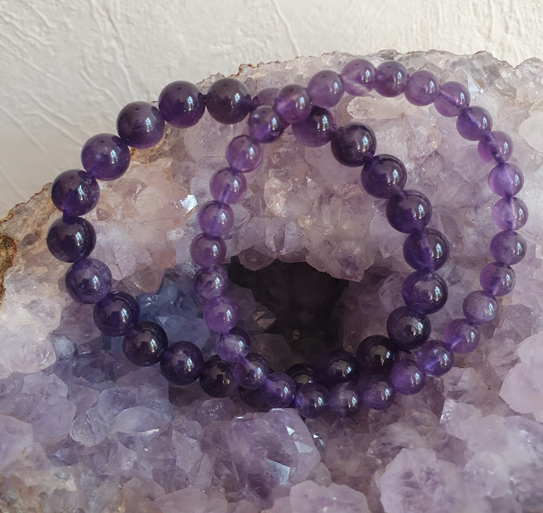 Deux bracelets de perles d'améthyste violette sur une géode de cristal violet.