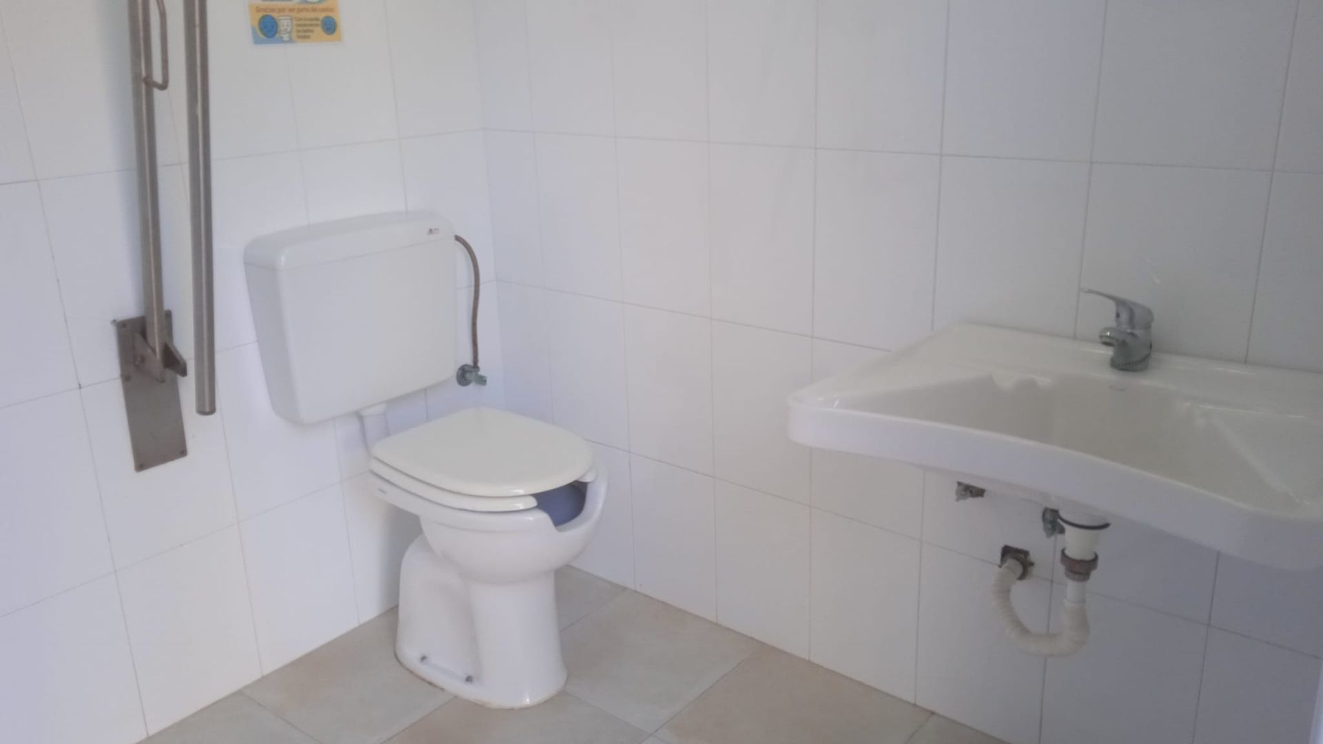 Baño accesible blanco con inodoro y lavabo.